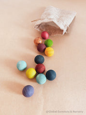 Vibrant dyed wooden balls for crafting and learning, set of 12 in a tan or pink bag.