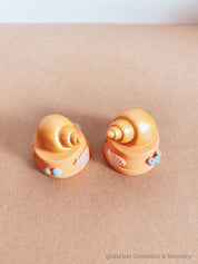 Miniature orange ocean shell on a stand, perfect for underwater-themed adventures or decor.