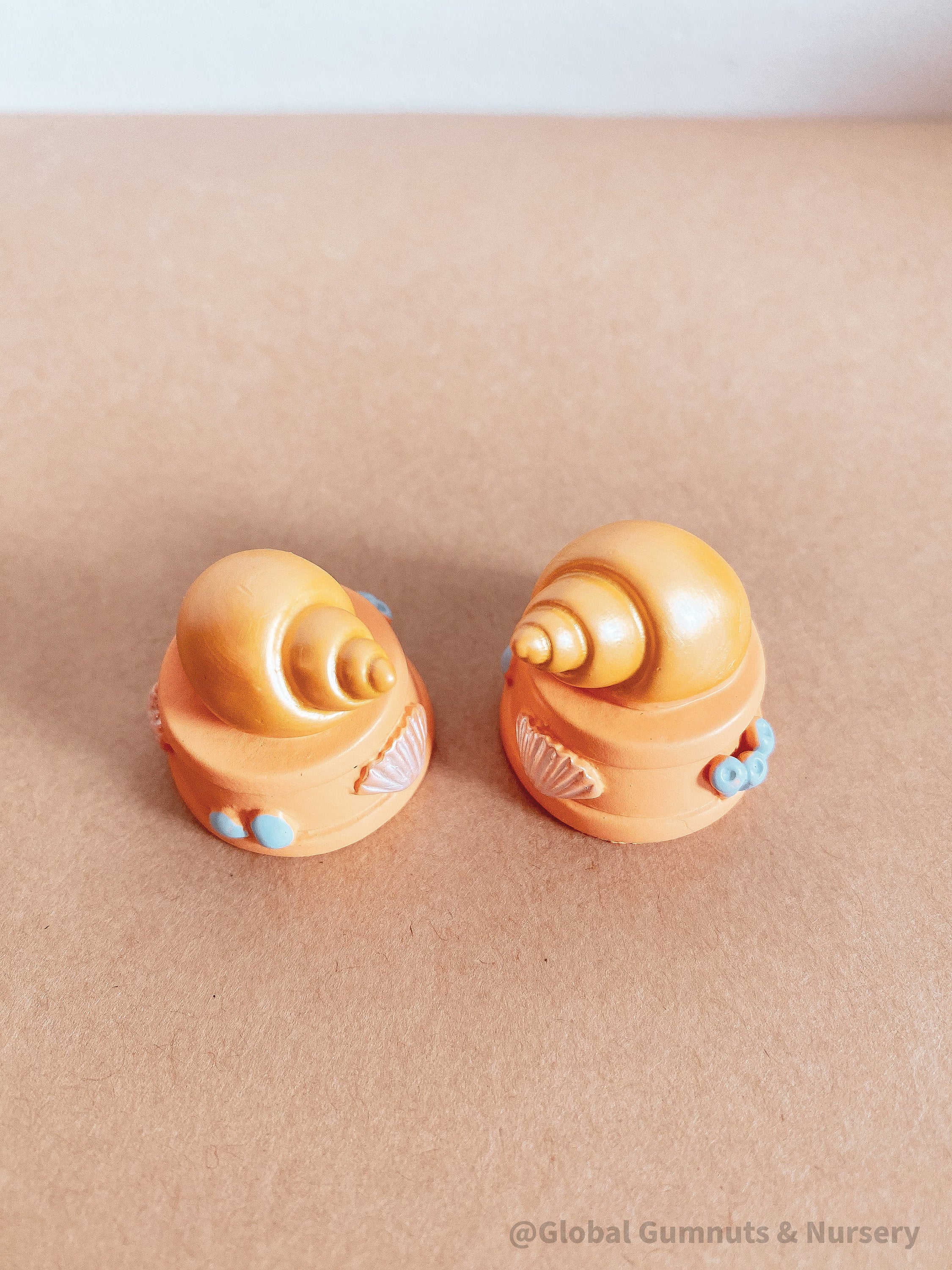 Miniature orange ocean shell on a stand, perfect for underwater-themed adventures or decor.