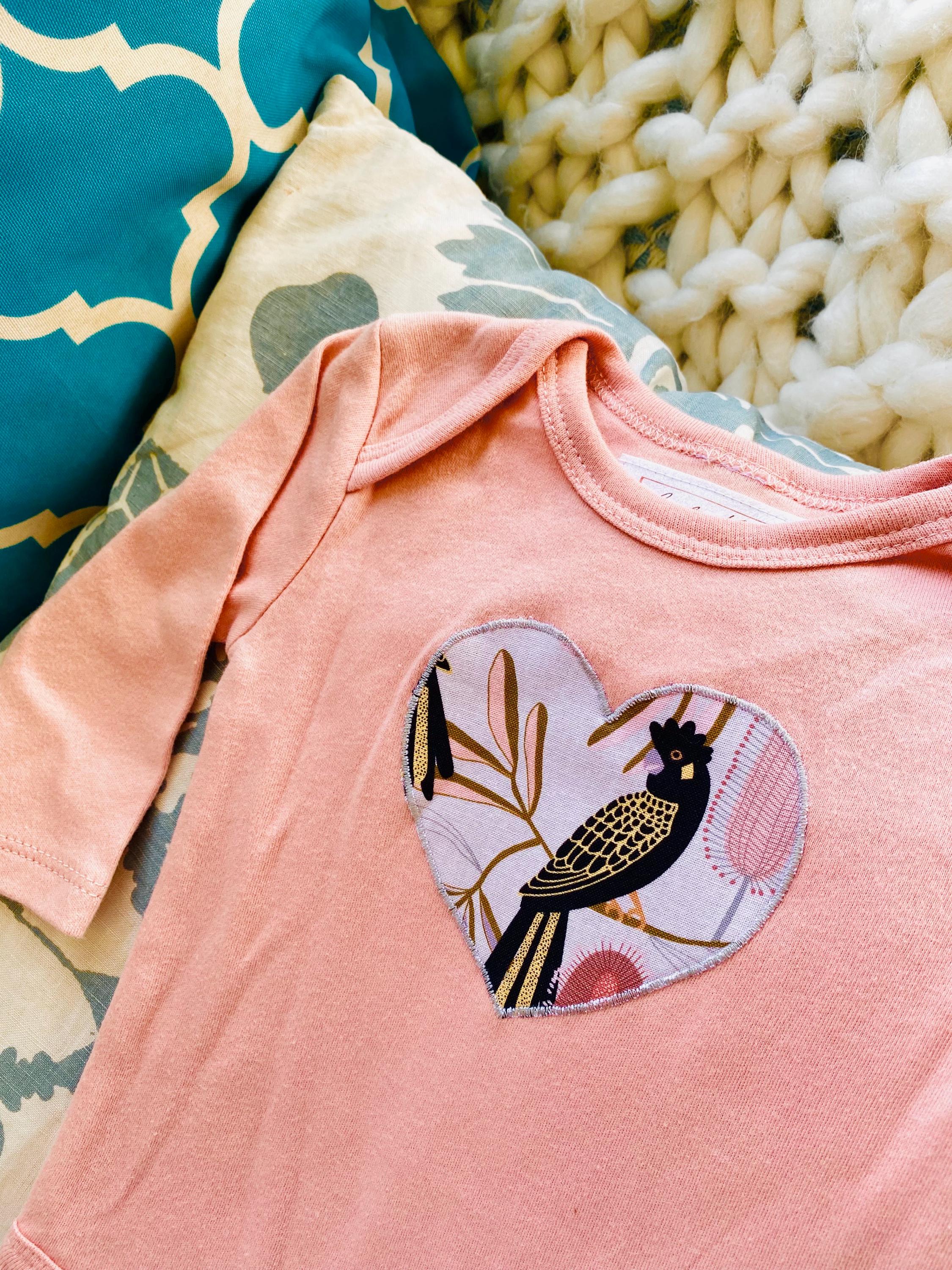 Peach Black Cockatoo Onesie: 100% cotton onesie featuring a peach black cockatoo design, handmade in Western Australia.