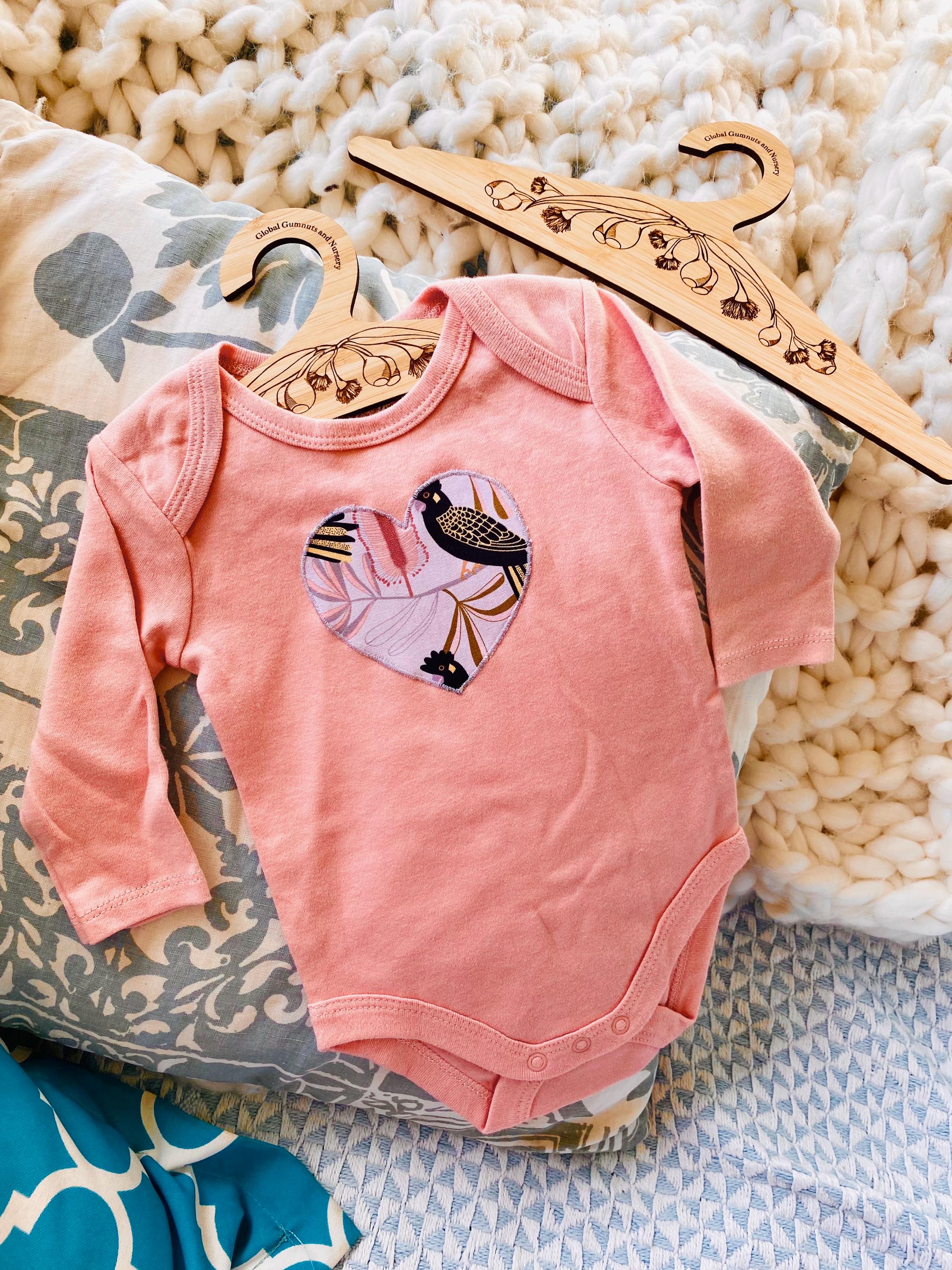 Peach Black Cockatoo Onesie: 100% cotton onesie featuring a peach black cockatoo design, handmade in Western Australia.