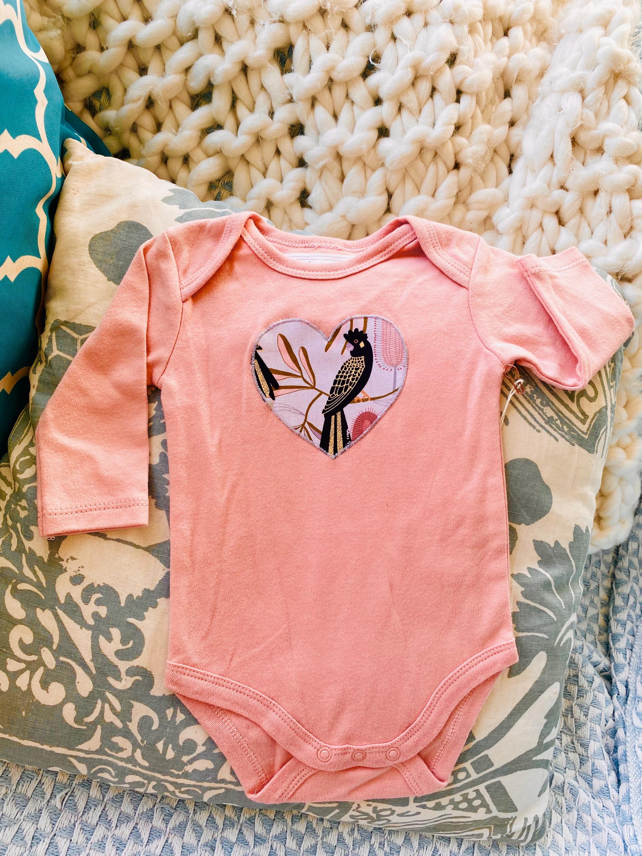 Peach Black Cockatoo Onesie: 100% cotton onesie featuring a peach black cockatoo design, handmade in Western Australia.