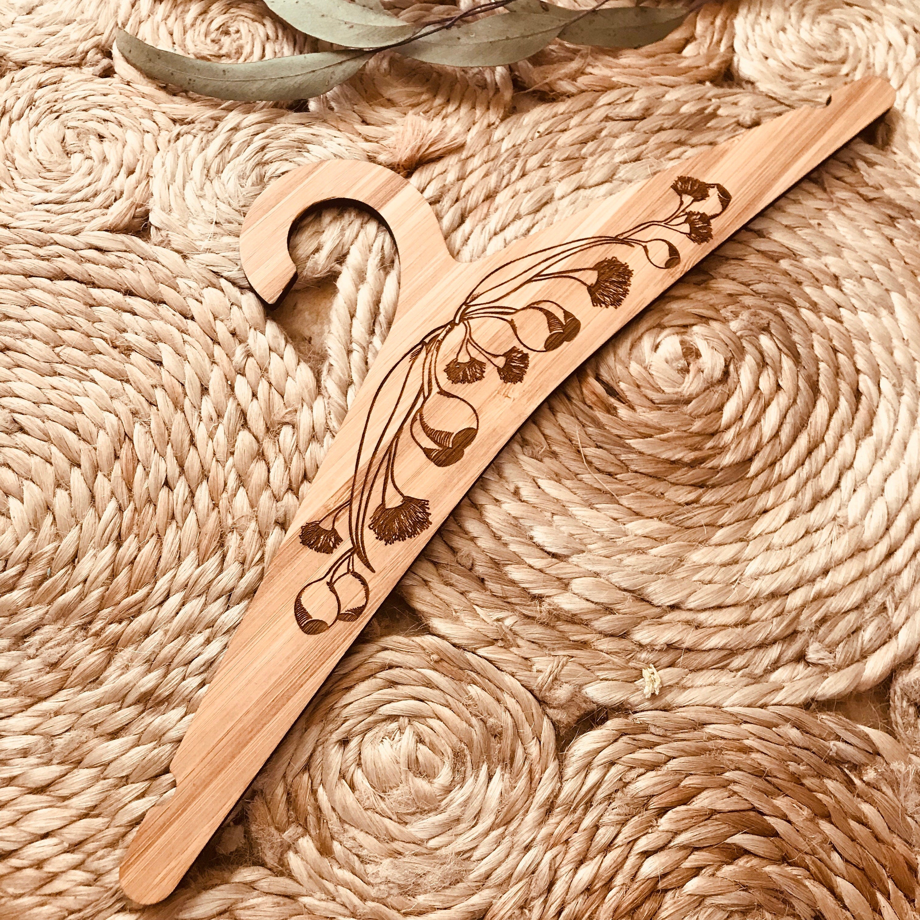 Wooden coat hanger featuring gumnuts and eucalyptus designs, bringing a touch of Australian nature to your closet.