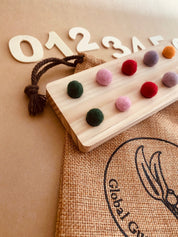 tens board with felt balls and numbers: educational toy with mini felt balls and wooden numbers, made from 100% nz wool, for play-based counting activities.