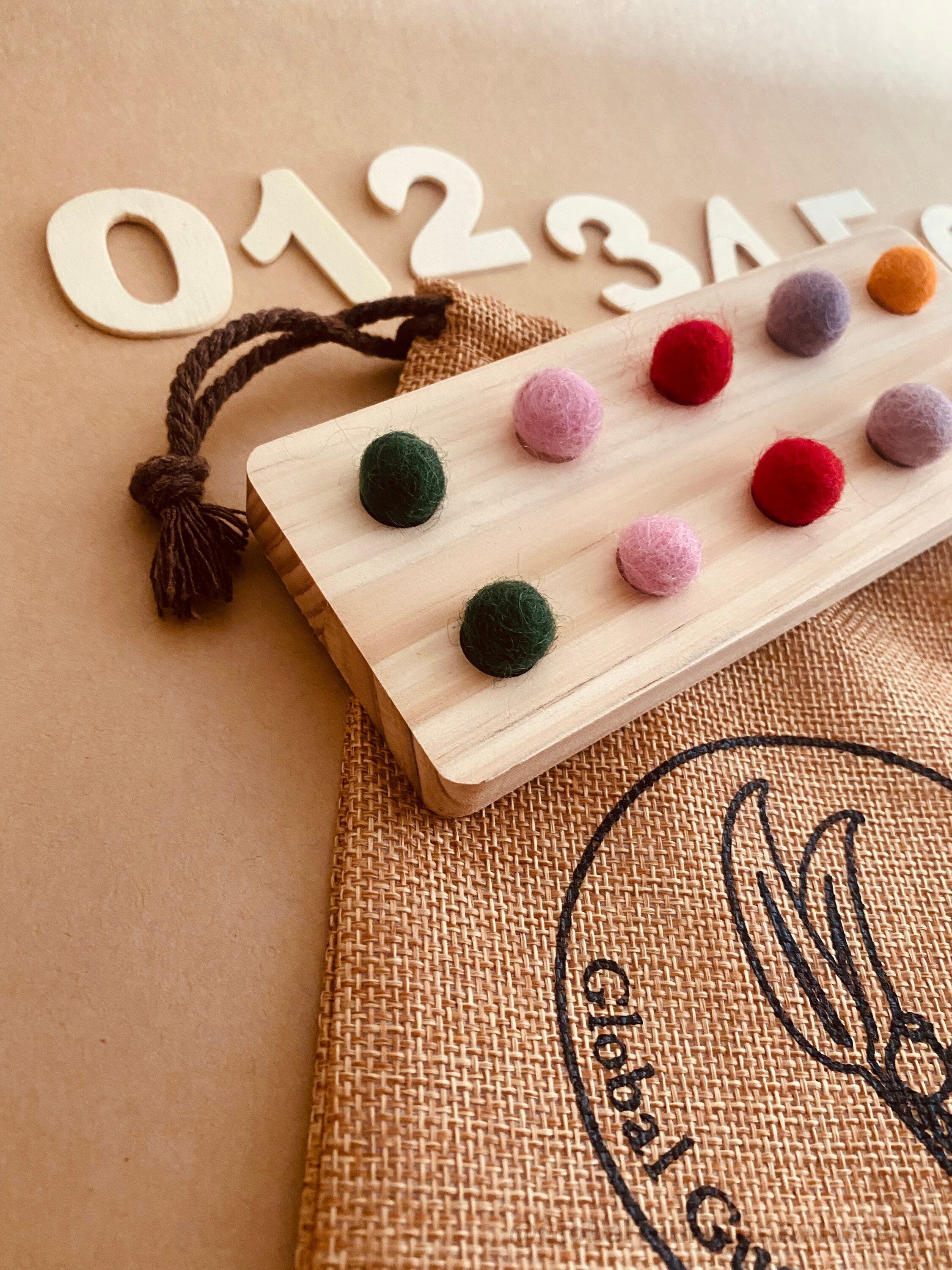 tens board with felt balls and numbers: educational toy with mini felt balls and wooden numbers, made from 100% nz wool, for play-based counting activities.