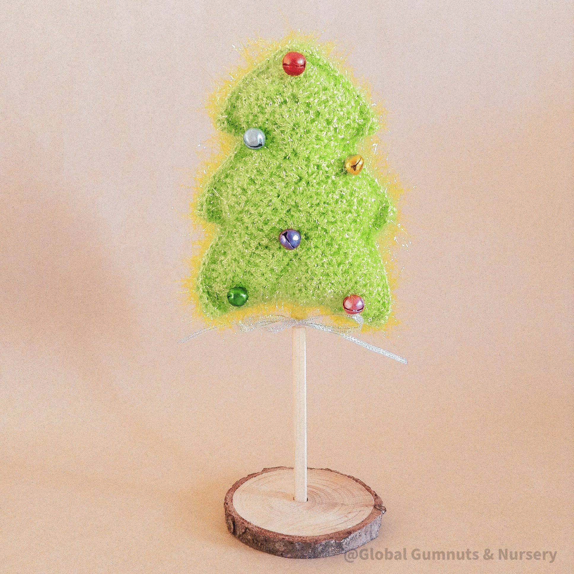 Crochet Christmas tree adorned with colorful bells. A cheerful, handmade addition to holiday decor.