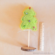Crochet Christmas tree adorned with colorful bells. A cheerful, handmade addition to holiday decor.