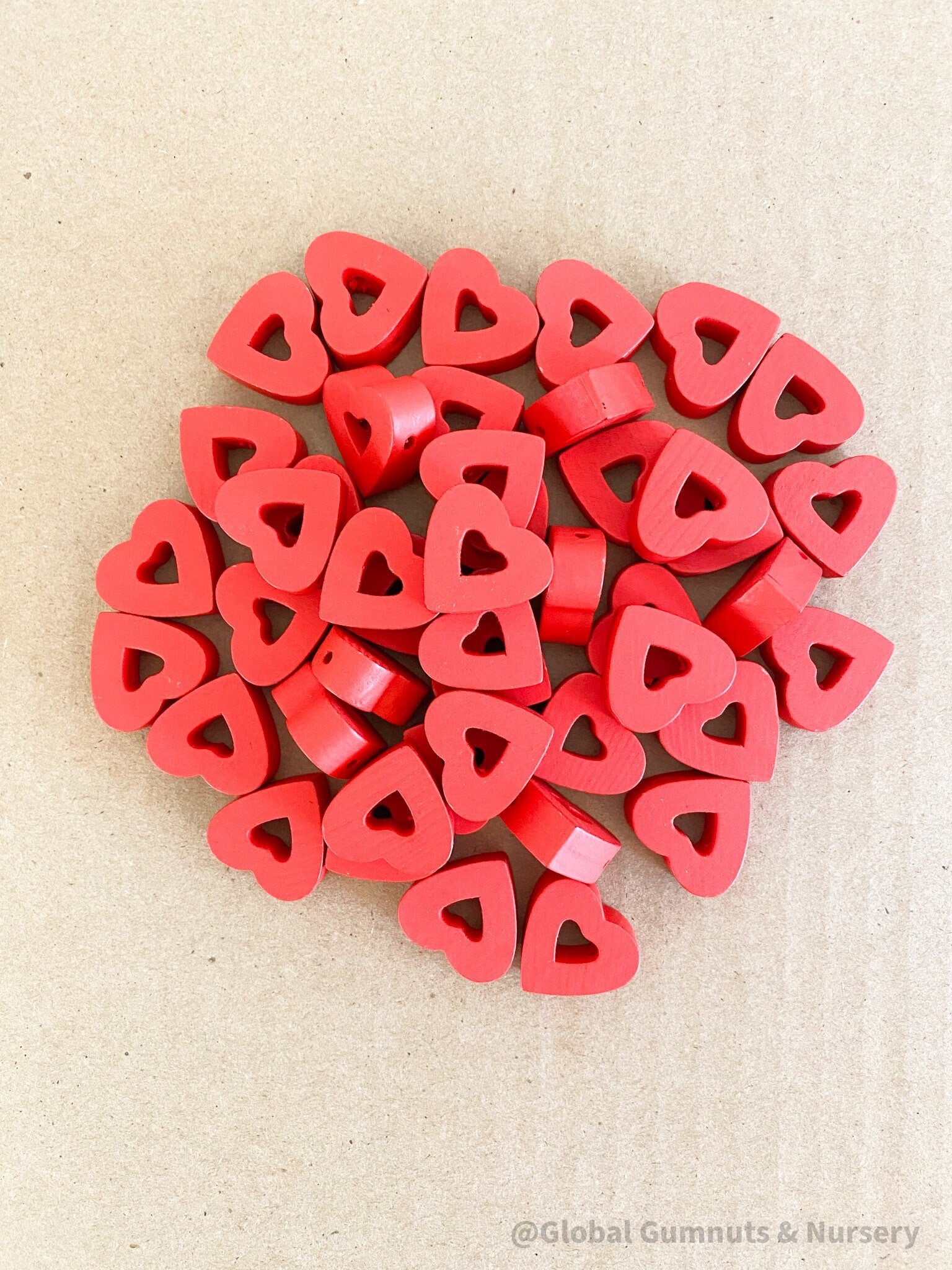 Whimsical red wooden heart beads, ideal for Valentine's Day crafts and projects.