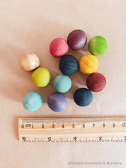Vibrant dyed wooden balls for crafting and learning, set of 12 in a tan or pink bag.
