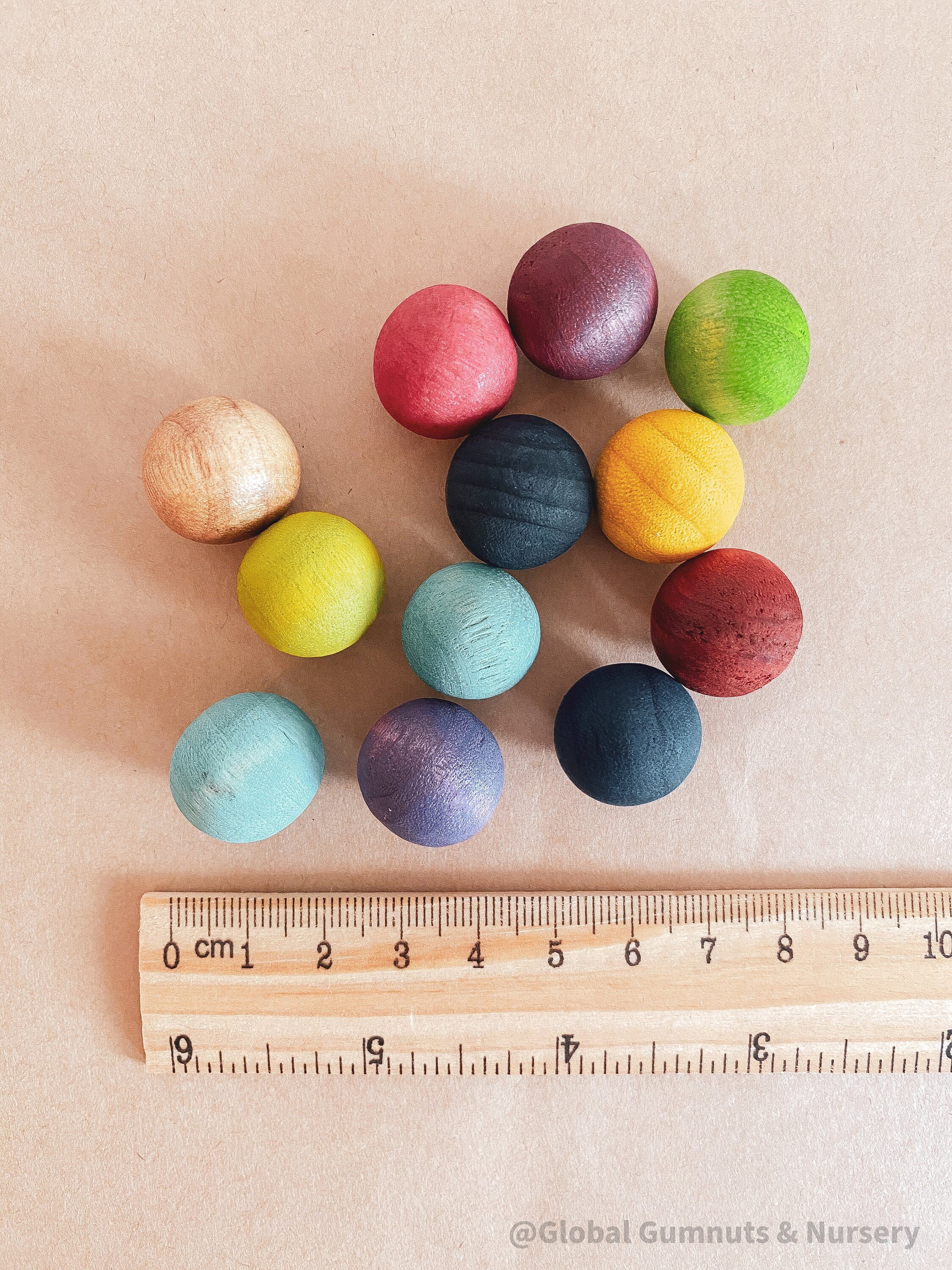 Vibrant dyed wooden balls for crafting and learning, set of 12 in a tan or pink bag.
