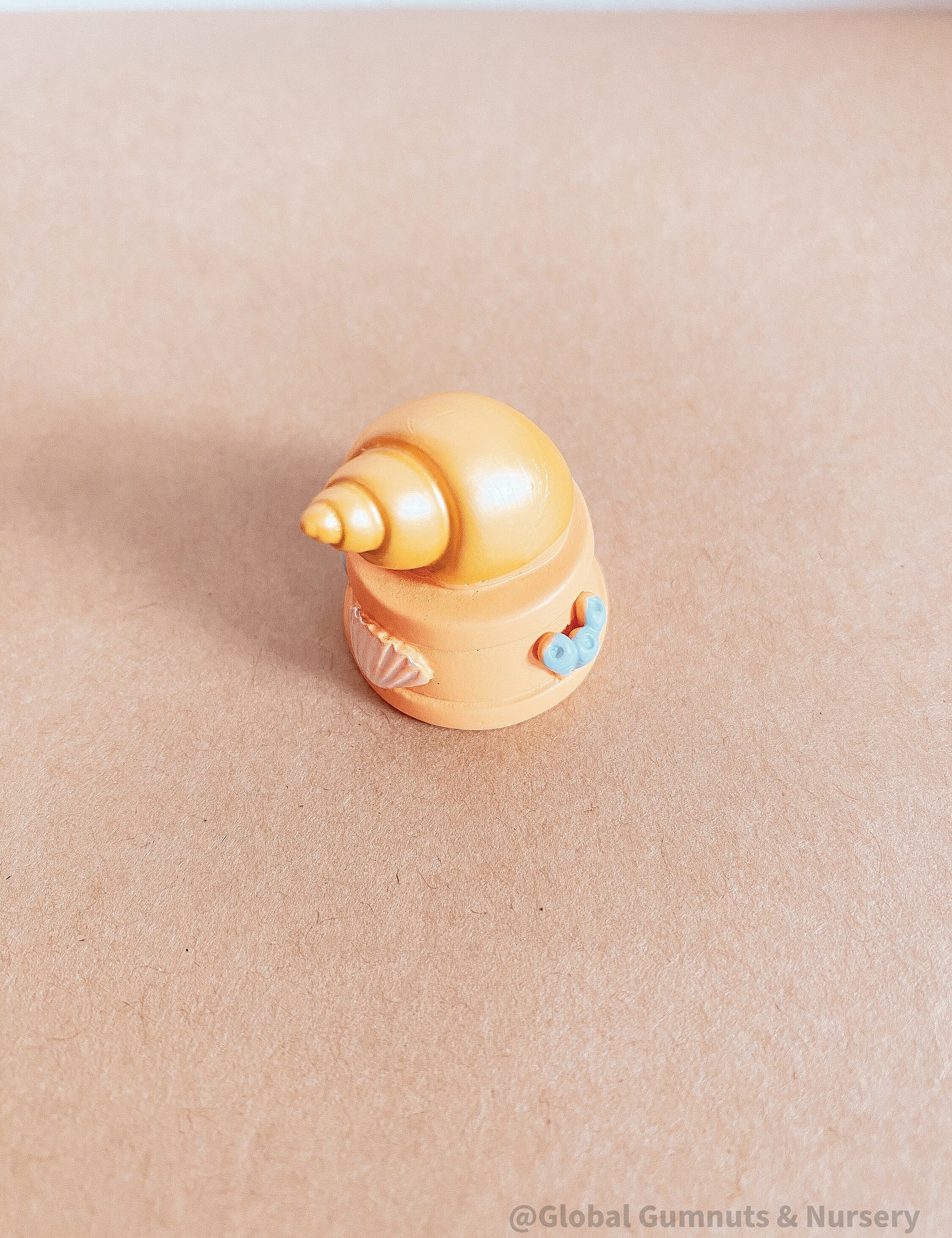 Miniature orange ocean shell on a stand, perfect for underwater-themed adventures or decor.
