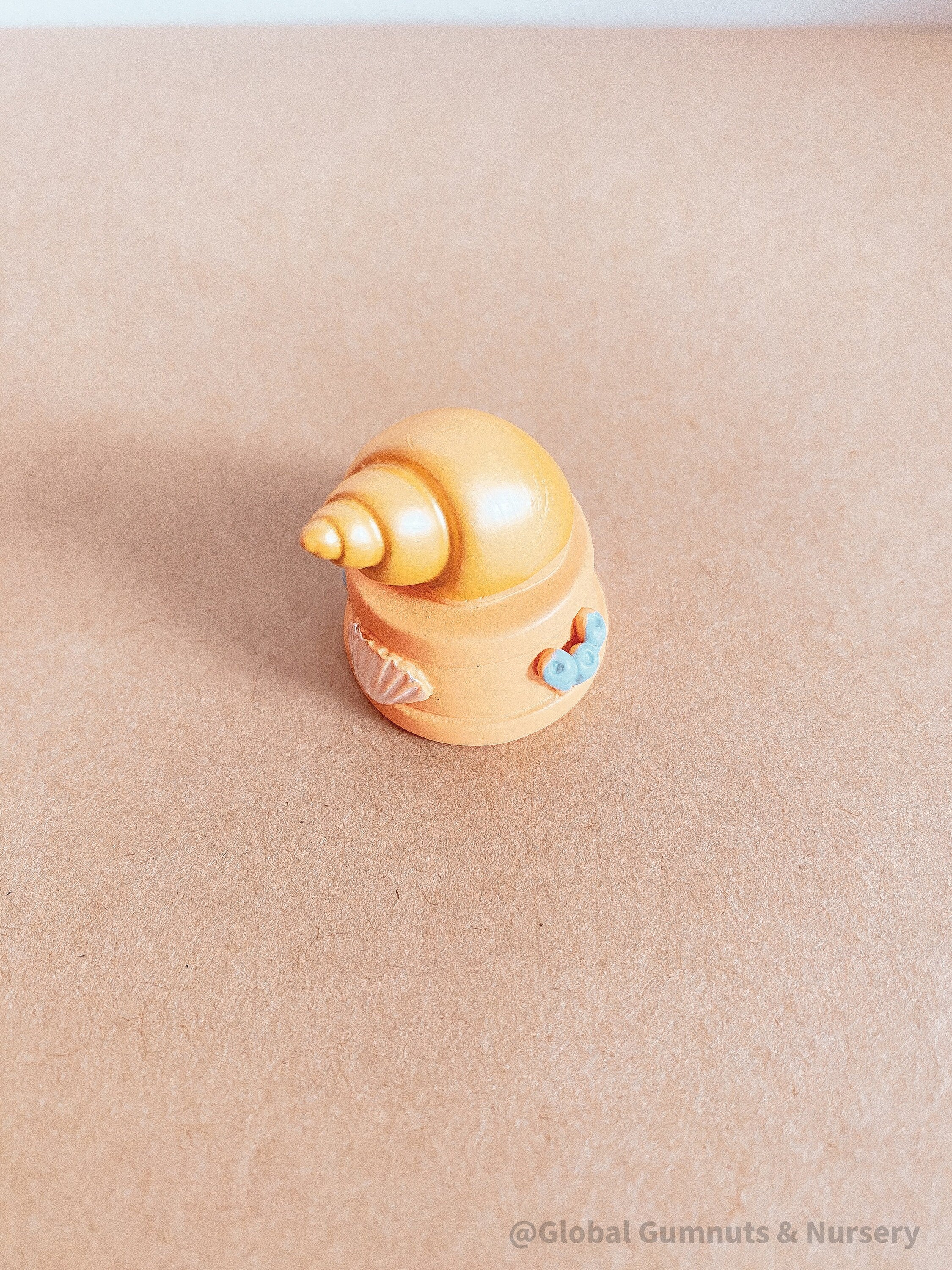 Miniature orange ocean shell on a stand, perfect for underwater-themed adventures or decor.
