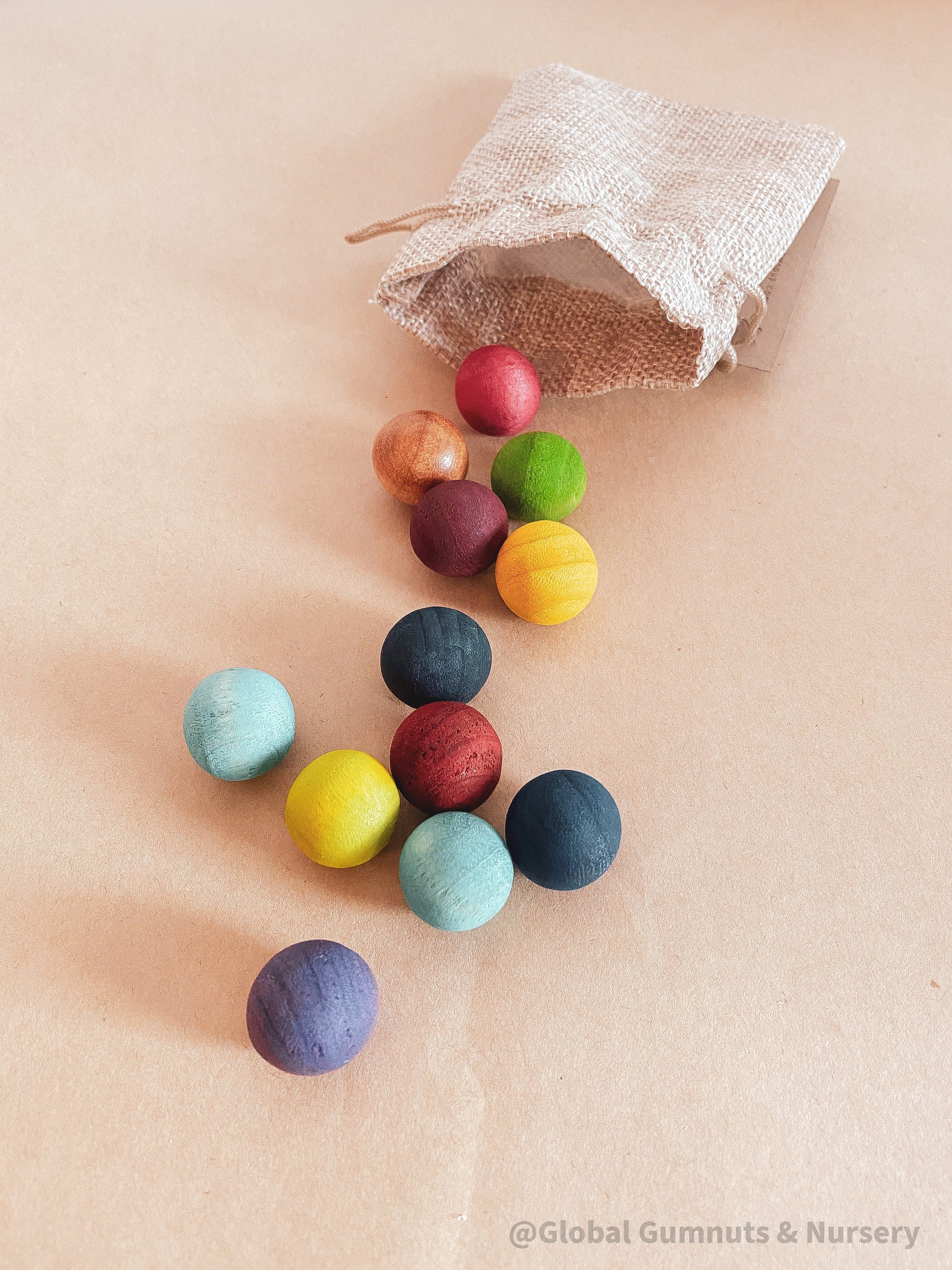 Vibrant dyed wooden balls for crafting and learning, set of 12 in a tan or pink bag.
