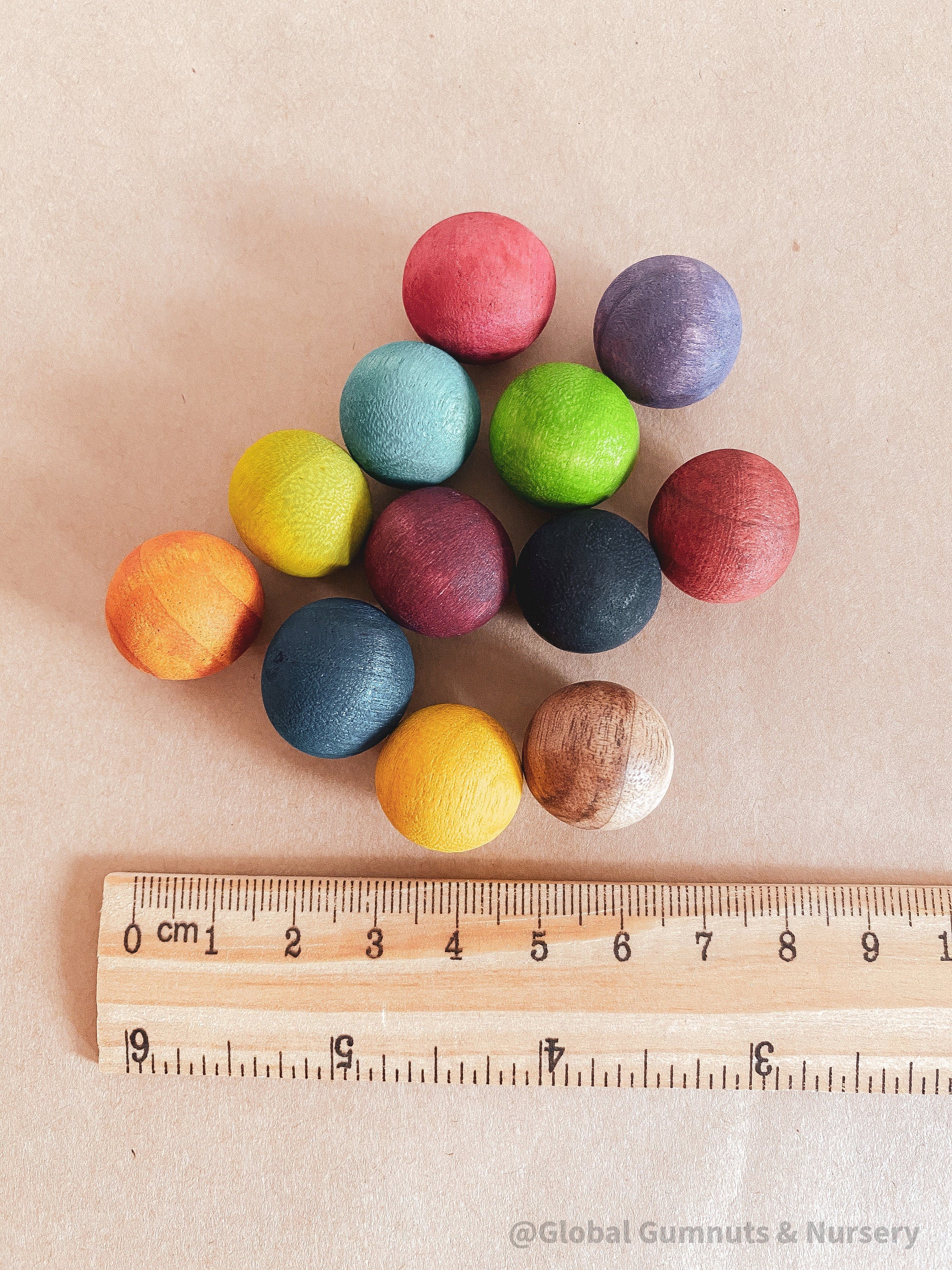 Vibrant dyed wooden balls for crafting and learning, set of 12 in a tan or pink bag.
