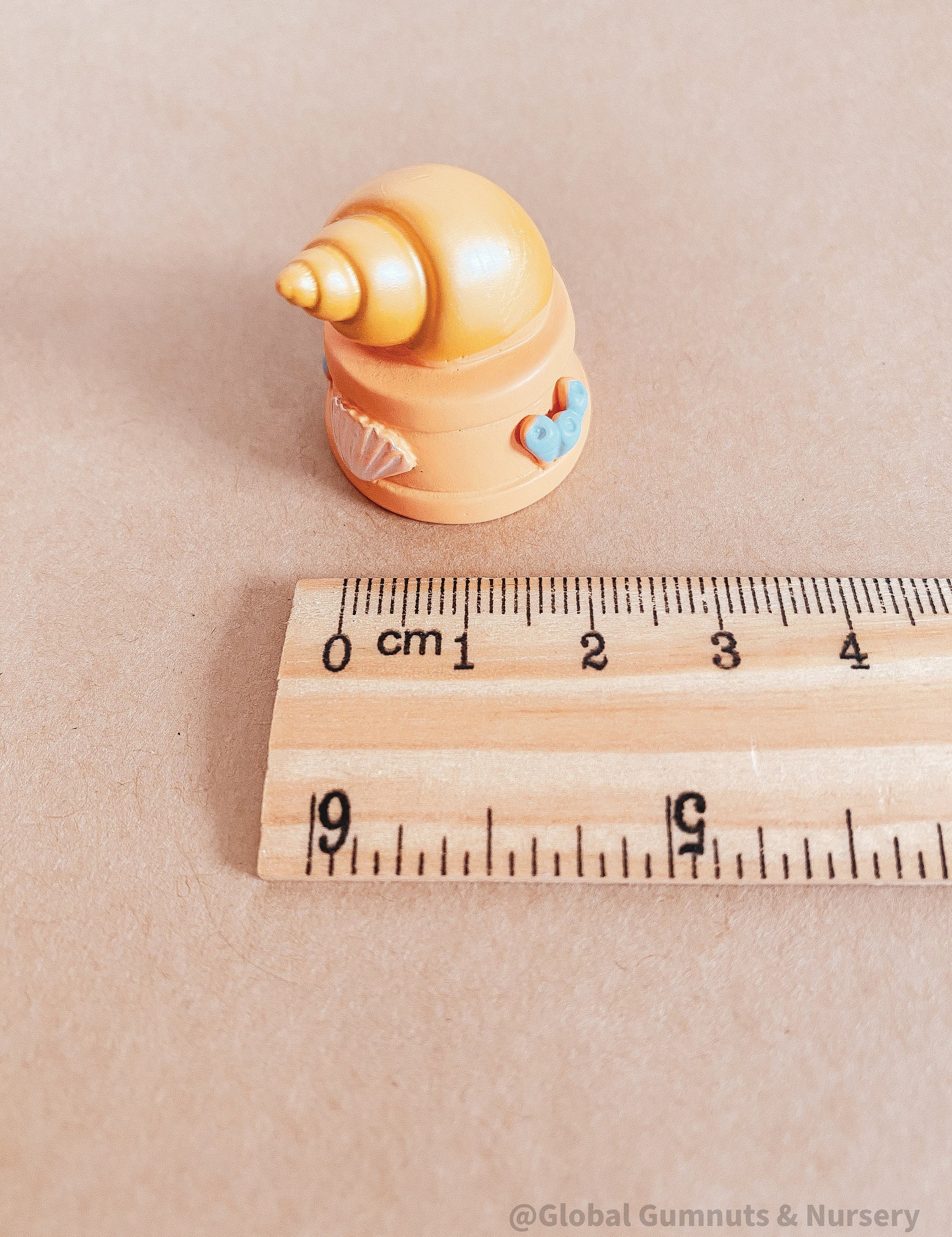 Miniature orange ocean shell on a stand, perfect for underwater-themed adventures or decor.
