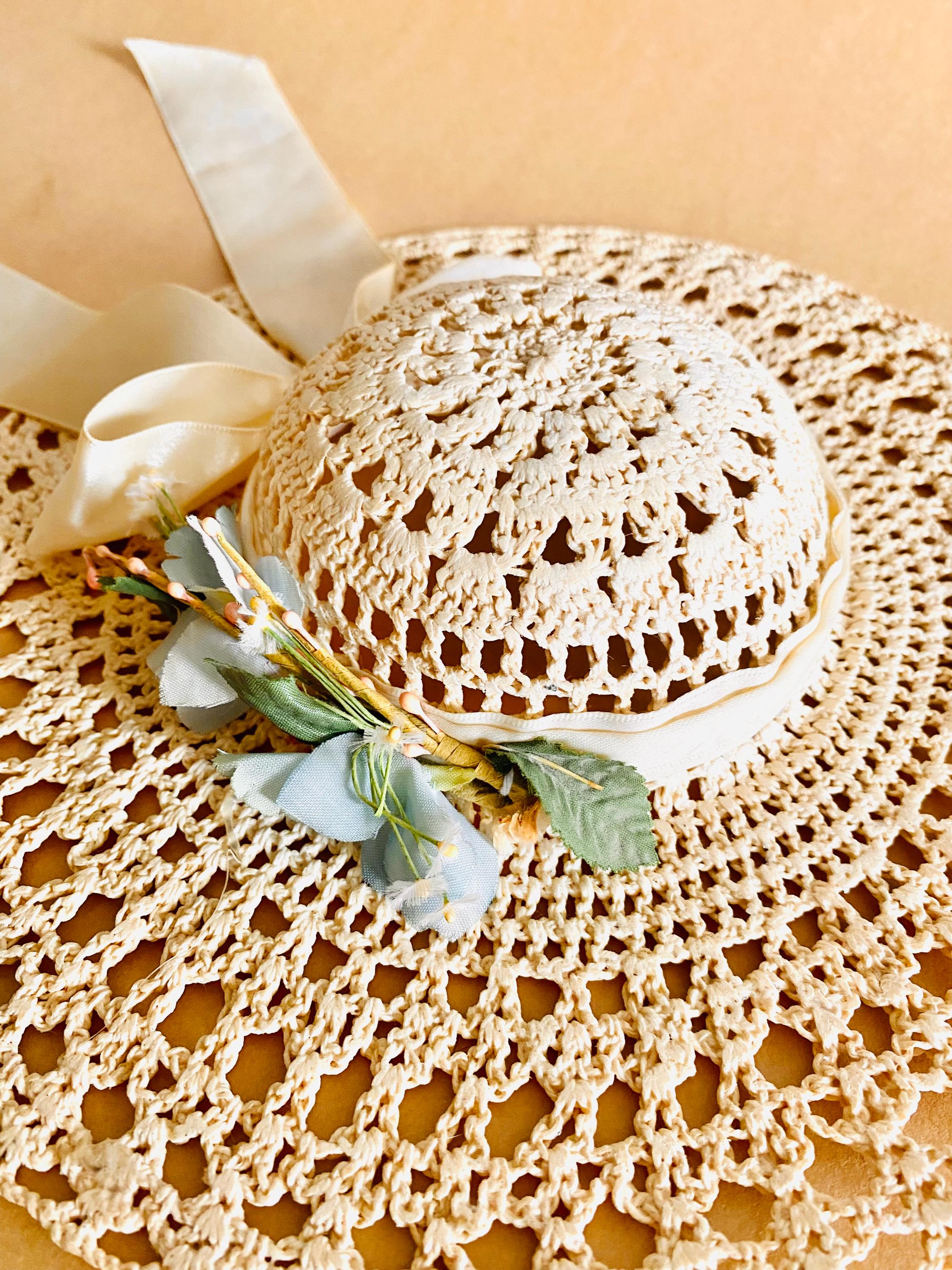 Vintage crochet hat with faux flowers and golden ribbon, offering timeless elegance.