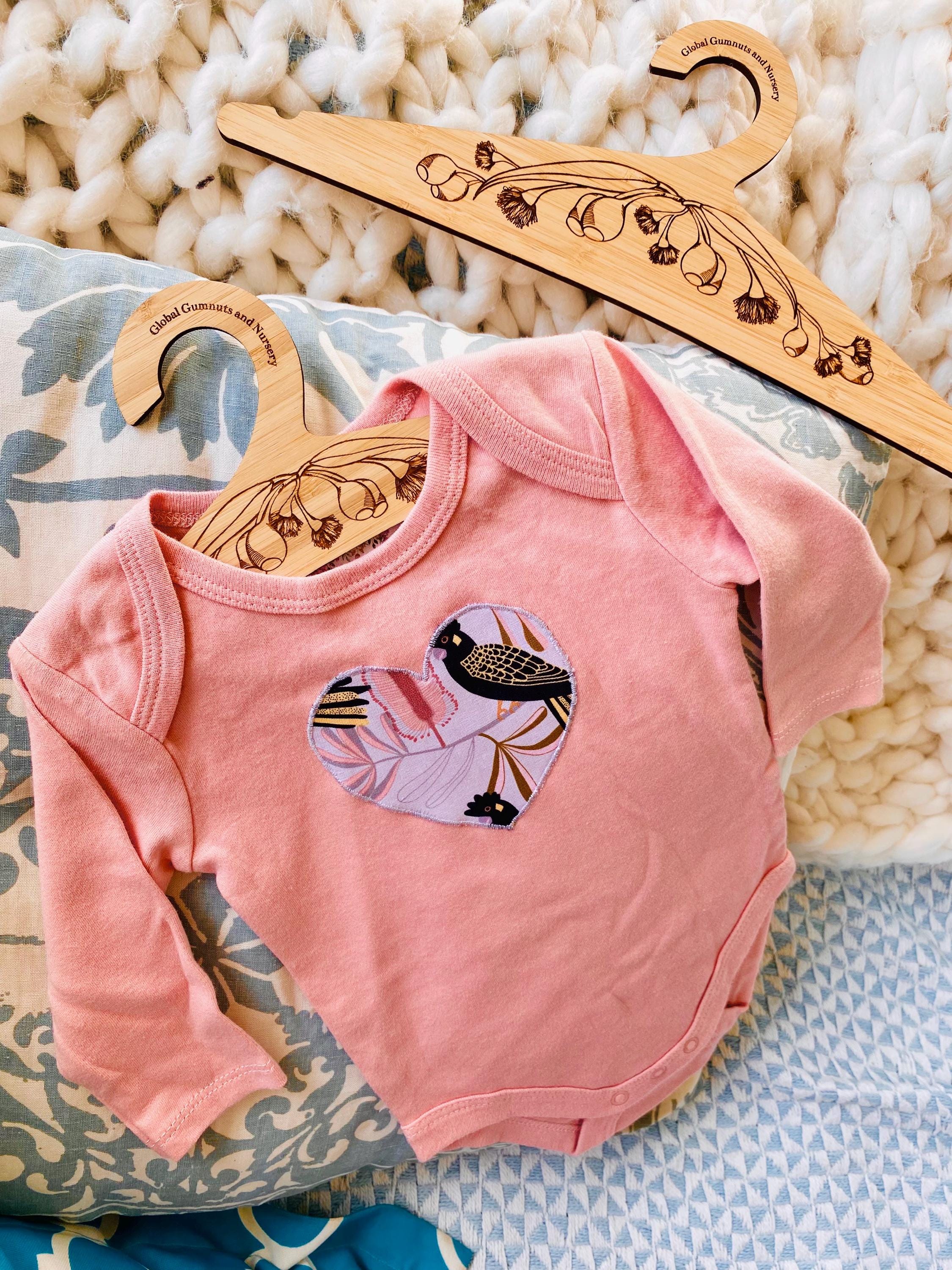 Wooden coat hanger featuring gumnuts and eucalyptus designs, bringing a touch of Australian nature to your closet.